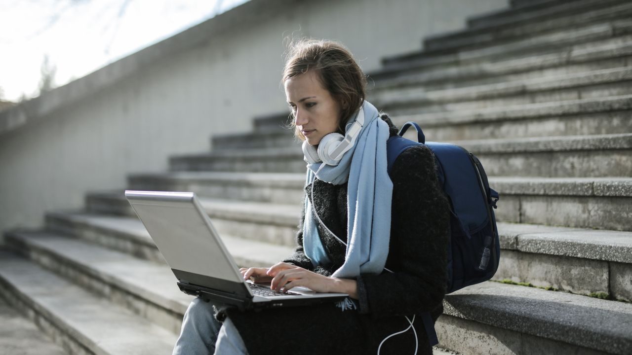 Uno studente seduto sui gradini lavora al laptop