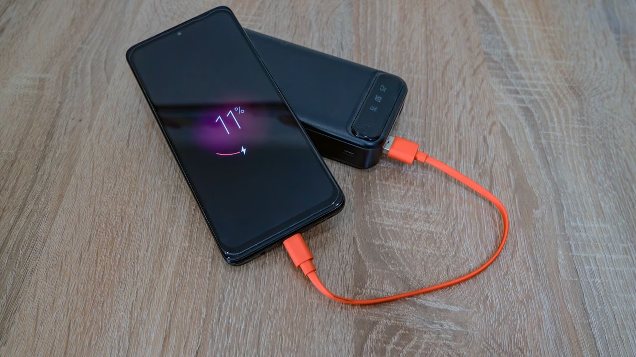 Two smartphones charging with an orange cable