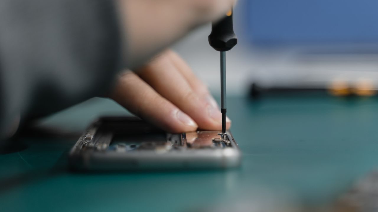 A technician repairing a smartphone with tools