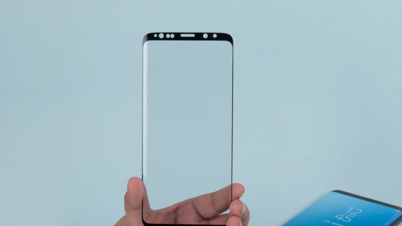 A hand holding a smartphone with a screen protector
