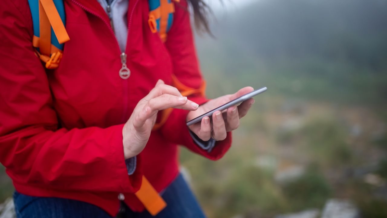 A traveler outdoors using a smartphone — K2J Tech tourist tech guide, Sarandë